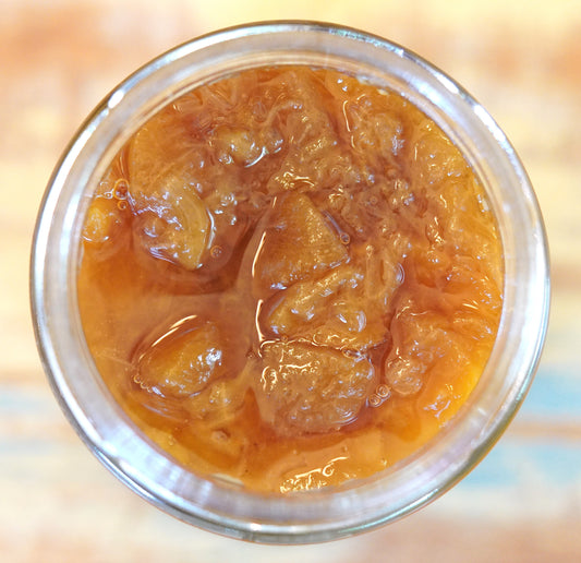 Open jar of Peach Old Fashioned, which has chunky pieces of peach with bourbon and cloves